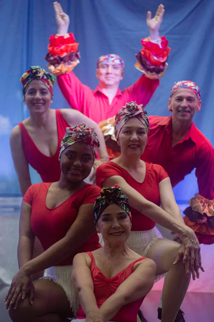Integrantes del Elenco Danzarte en escena con vestuario rojo, turbantes y mangas de vuelos de colores